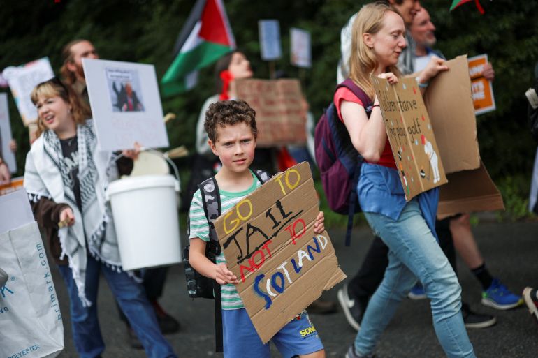 A boy holds a placard as demonstrators protest the visit of U.S. President Donald Trump, in Balmedie, near Aberdeen, Scotland, Britain, July 28, 2025. REUTERS/Hannah McKay