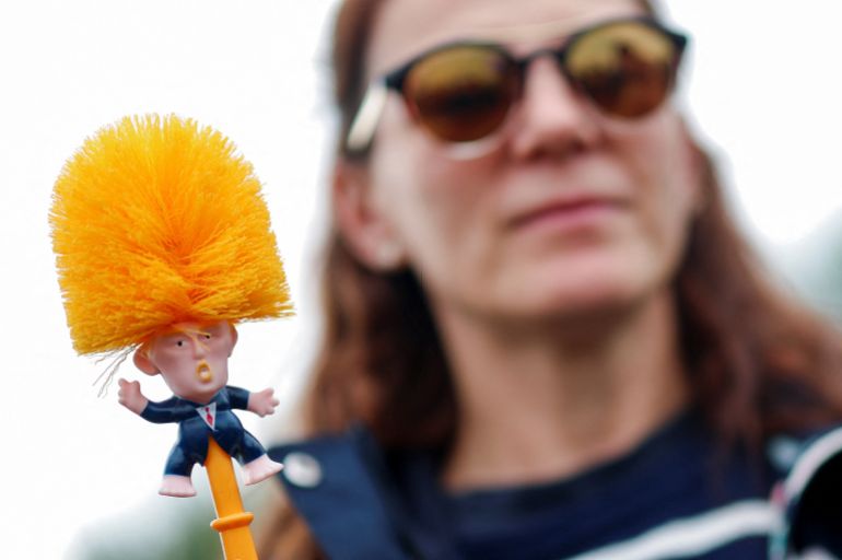 A woman holds a toilet brush depicting U.S. President Donald Trump as demonstrators protest the visit of U.S. President Donald Trump, in Balmedie, near Aberdeen, Scotland, Britain, July 28, 2025. REUTERS/Hannah McKay