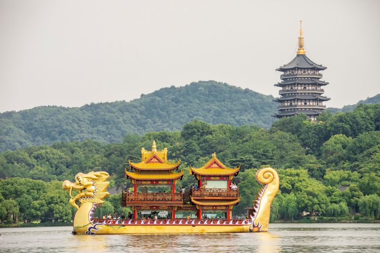 HangZhou China Jun 13th 2023: The dragon cruise in West Lake. Background is Leifeng Pagoda, a five story tall tower with eight sides, located on Sunset Hill south of the West Lake. ; Shutterstock ID 2330040363; purchase_order: aj; job: ; client: ; other: