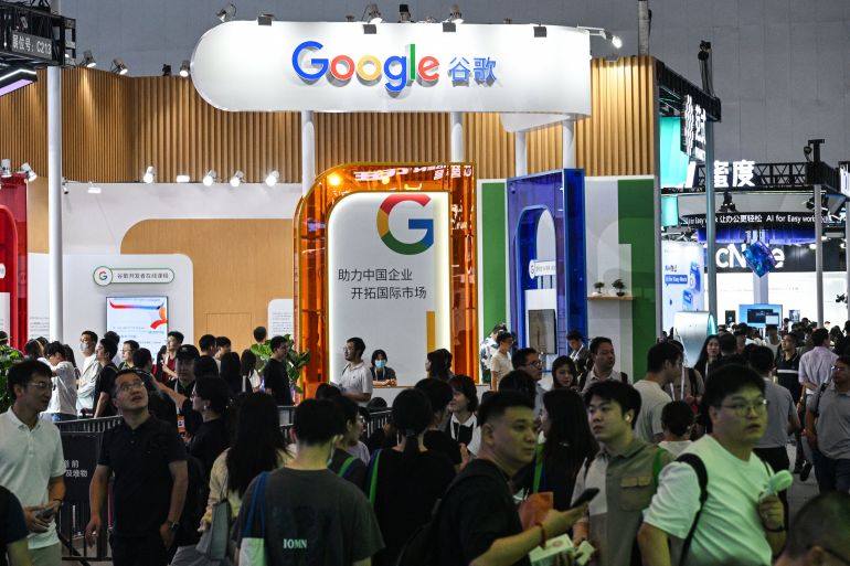 People walk next to a Google stand during the World Artificial Intelligence Conference (WAIC) at the Shanghai World Expo and Convention Center in Shanghai on July 28, 2025. (Photo by HECTOR RETAMAL / AFP)