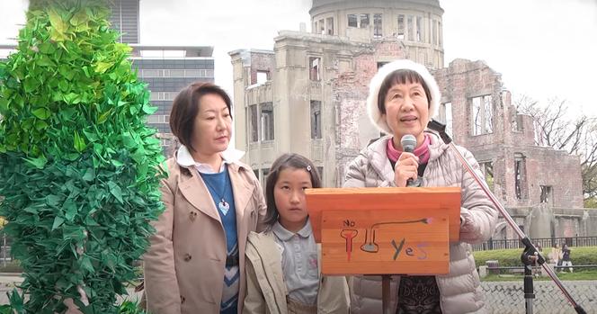 توشيكو تاناكا في عام 2014 ، خلال تدخل في نصب هيروشيما للسلام ، مع ابنته وحفيدتها.