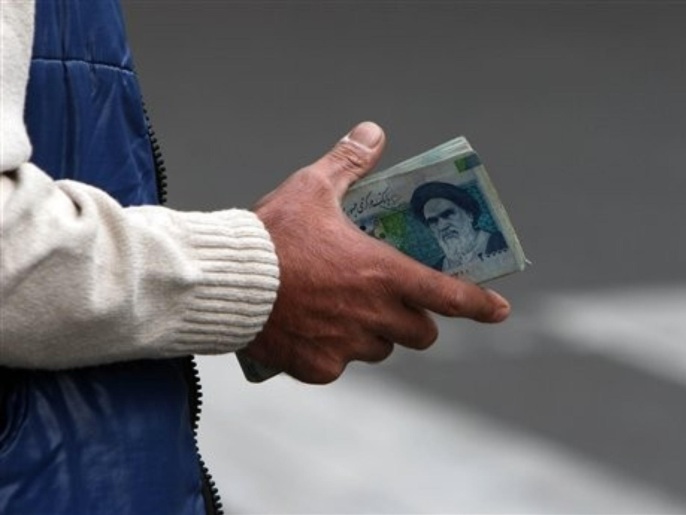 FILE - In this Thursday, Oct. 30, 2008 file photo, an Iranian money changer holds currency with Ayatollah Ruhollah Khomeini's image in Tehran, Iran. Iran's currency has hit a new record low to the U.S. dollar, two days after President Barack Obama signed a bill applying penalties against Iran's central bank as the West looks to pressure Tehran over its nuclear program. State radio said the exchange rate hovered around 16,800 riyals to the dollar, marking a roughly 10 percent slide compared to Thursday's rate of 15,200 riyals to the dollar.