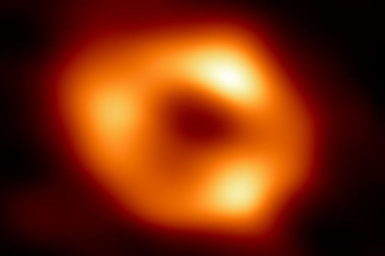 This is the first image of Sgr A*, the supermassive black hole at the centre of our galaxy. It’s the first direct visual evidence of the presence of this black hole. It was captured by the Event Horizon Telescope (EHT), an array which linked together eight existing radio observatories across the planet to form a single “Earth-sized” virtual telescope. The telescope is named after the event horizon, the boundary of the black hole beyond which no light can escape. Although we cannot see the event horizon itself, because it cannot emit light, glowing gas orbiting around the black hole reveals a telltale signature: a dark central region (called a shadow) surrounded by a bright ring-like structure. The new view captures light bent by the powerful gravity of the black hole, which is four million times more massive than our Sun. The image of the Sgr A* black hole is an average of the different images the EHT Collaboration has extracted from its 2017 observations. In addition to other facilities, the EHT network of radio observatories that made this image possible includes the Atacama Large Millimeter/submillimeter Array (ALMA) and the Atacama Pathfinder EXperiment (APEX) in the Atacama Desert in Chile, co-owned and co-operated by ESO is a partner on behalf of its member states in Europe.