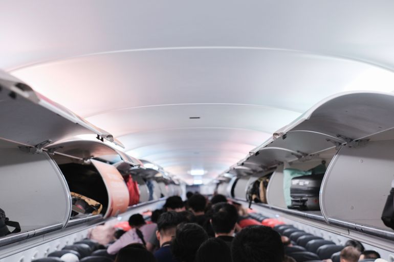 overhead locker on airplane,Passenger put cabin bag cabin on the top shelf. Travel concept