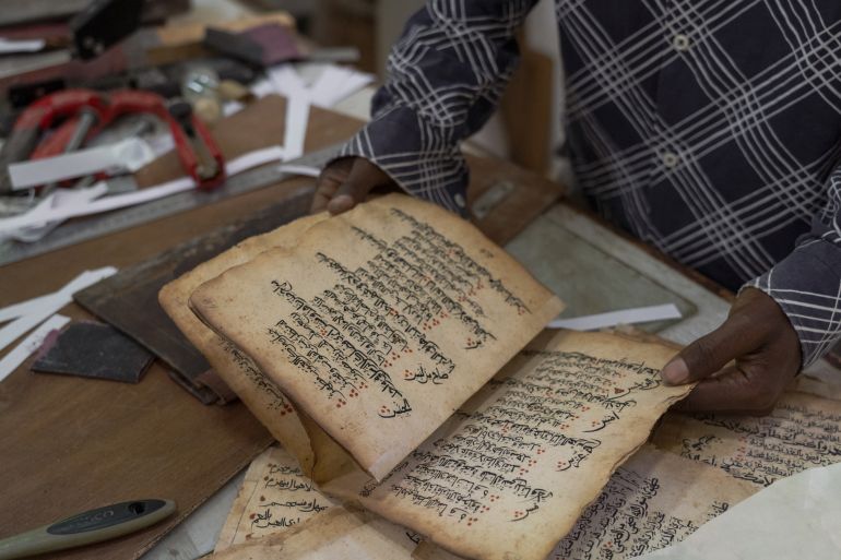 An old manuscript that Sherif and his employee Elias Bule are restoring [Jaclynn Ashly/Al Jazeera]