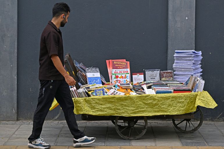 A pedestrian walks past a book cart along a roadside in Srinagar on August 7, 2025.