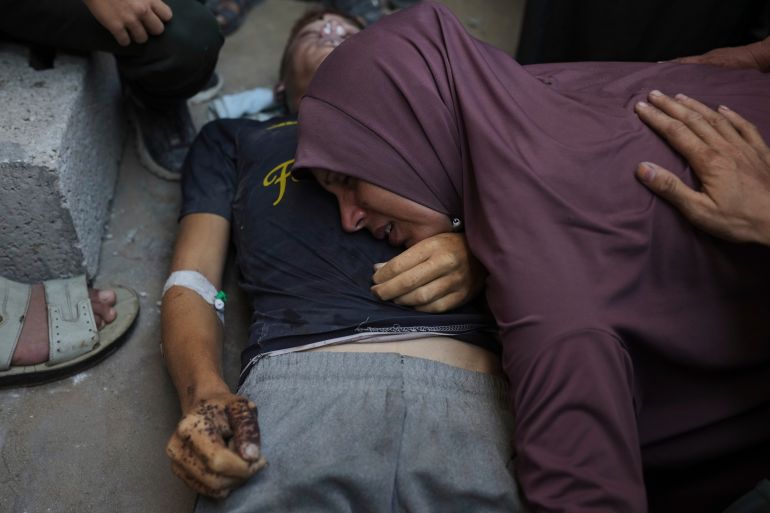 A Palestinian mother mourns over the body of her young son, Mohammed Al-Matouq, who was killed while trying to reach aid trucks entering northern Gaza Strip through the Zikim crossing with Israel, at Shifa Hospital in Gaza City, Monday, Aug. 4, 2025. (AP Photo/Jehad Alshrafi)