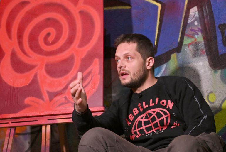 Bosnian street artist Benjamin Cengic sits next to his signature 'Flower Graffitti' in his creative space, in Sarajevo on May 22, 2025. (Photo by ELVIS BARUKCIC / AFP)