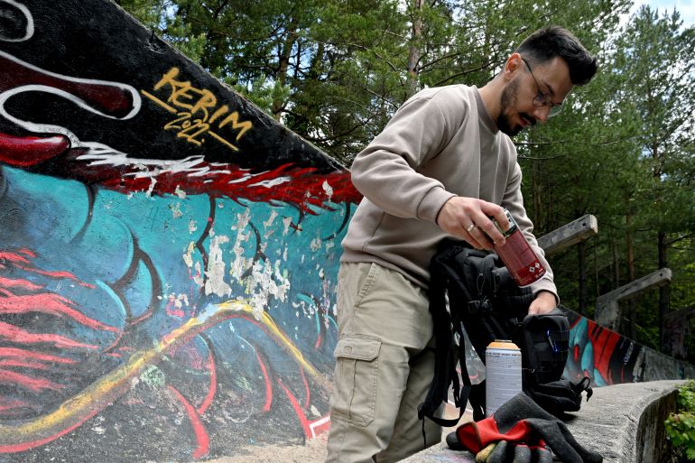Bosnian street artist Kerim Musanovic puts the finishing touches to his painting on the former Olympic bobsleigh track on Mount Trebevic, near Sarajevo, on May 26, 2025. (Photo by ELVIS BARUKCIC / AFP)