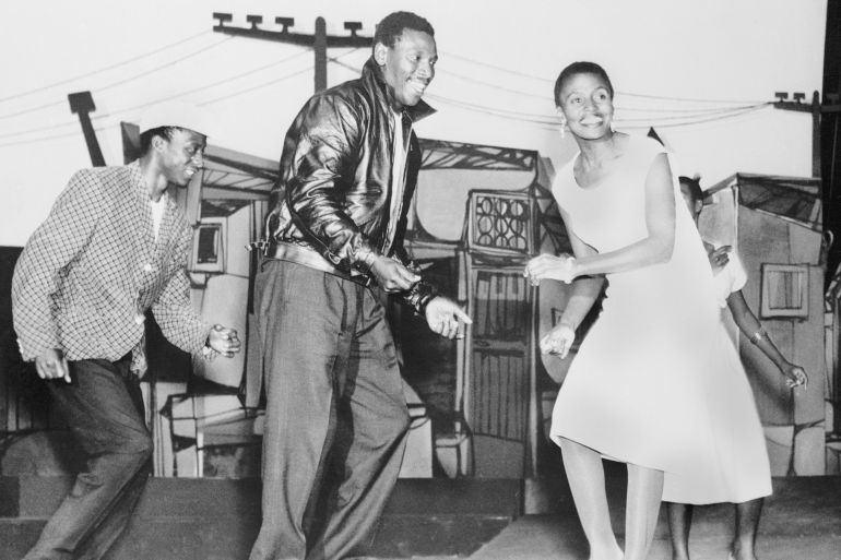 (Original Caption) Scene from King Kong. Johannesburg: American and British theater goers are likely to be seeing in the next season or so an all-African jazz opera that is a smash hit in South Africa and could become one in New York and London. The show, called King Kong is based on the real life story of zulu heavyweight champion Ezekiel Dhlamini who, after being knocked out by a mere middleweight lost his popularity, became a vicious bully, and ended up a murderer. In this scene from the show, African actor-singer Nathan Mdledle (center), as "King Kong," dances with his gangster-moll girl friend-played by Miriam Makeba, at an illicit liquor den.