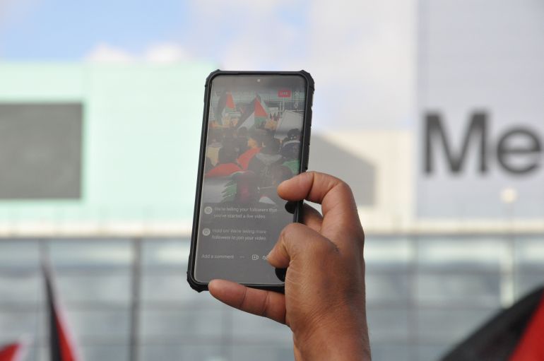 Salford, Greater Manchester, UK. 10.21.2023: Close up of pro Palestinian protester's phone live streaming the rally to social media. Outside BBC offices in Media City, Salford.