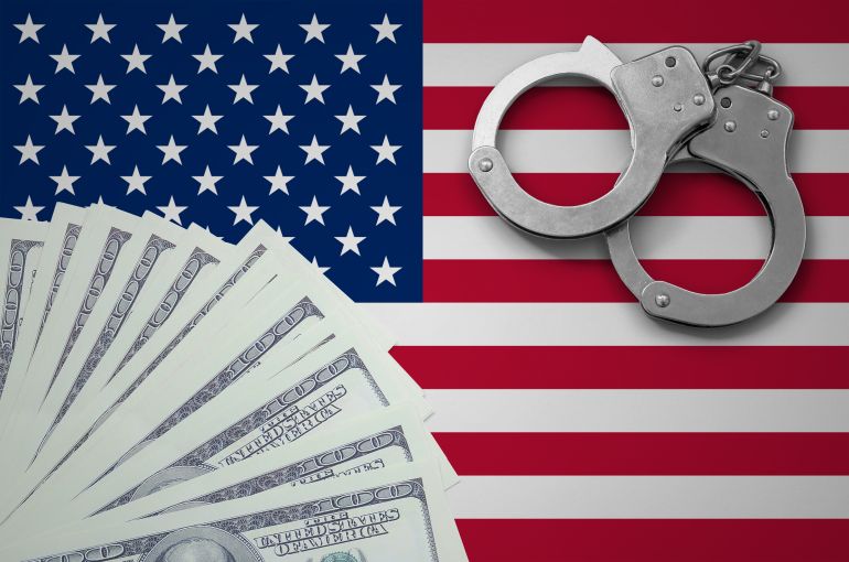 United States of America flag with handcuffs and a bundle of dollars. The concept of illegal banking operations in US currency