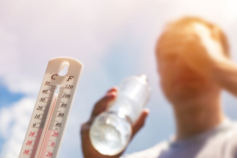 Man drinking water in extreme heat, Thermometer in summer day shows or indicate high temperature degree with sun in background.; Shutterstock ID 2340531097; purchase_order: ajnet; job: ; client: ; other: