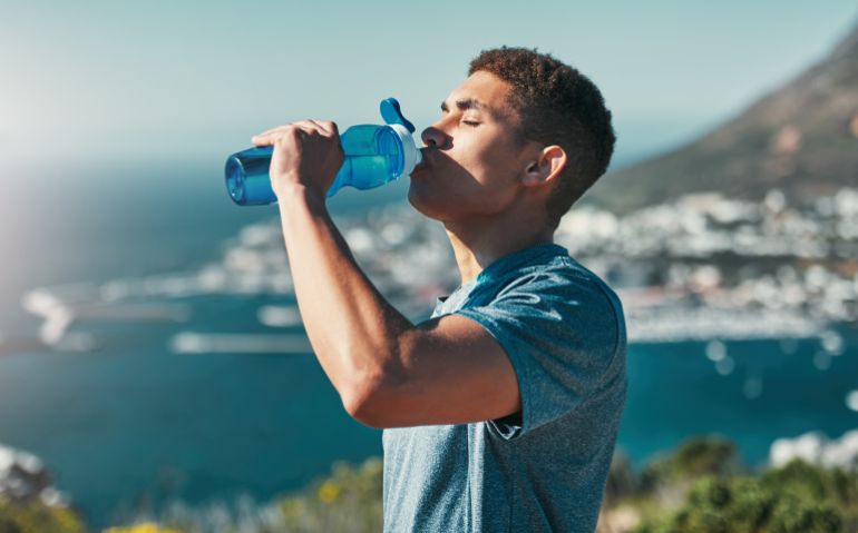 Fitness, man and drinking water outdoor for wellness, body health and nutrition benefits after exercise. Hydration, bottle and thirsty runner in nature with liquid for electrolytes on break or rest; Shutterstock ID 2507089357; purchase_order: ajnet; job: ; client: ; other: