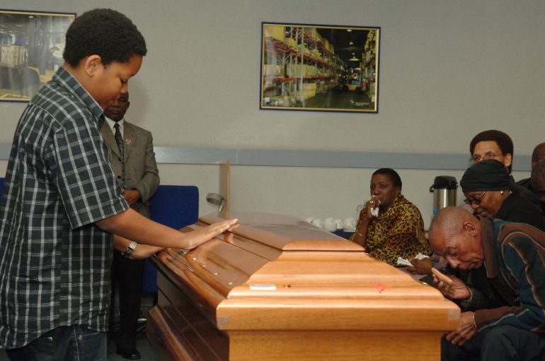 South African singing legend and activist "Mama Africa" Miriam Makeba's great grandchild Lindelane (L) says farewell to her on November 12, 2008 after her coffin arrived at Johannesburg's OR Tambo Airport from Italy, where she died age 76. Family and friends led a procession of cars to take the coffin from the airport to a mortuary in Soweto, radio reports said. The South African cabinet was discussing a state funeral for Makeba during its weekly meeting, said arts ministry spokesman Sandile Memela. AFP PHOTO / Jacoline Prinsloo (Photo by Jacoline Prinsloo / DFA / AFP)