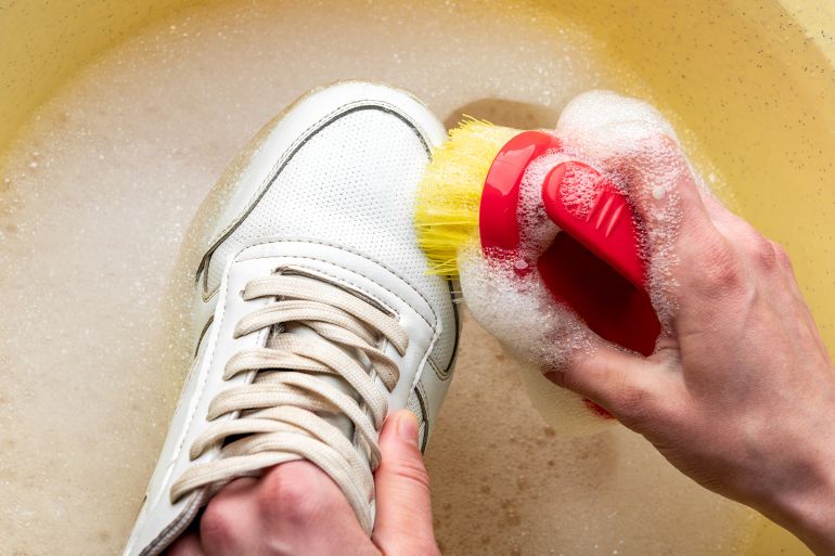 Sneakers in a wash basin with soapy water. Washing the dirty sneakers, cleaning the shoes.
