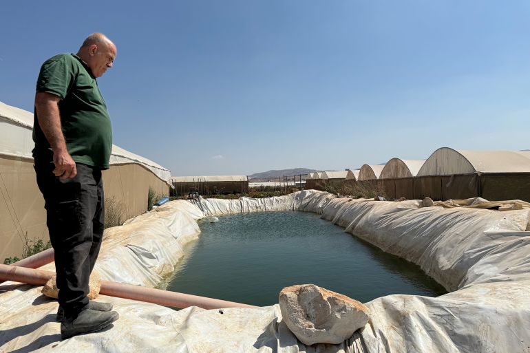 صورة للمزارع دياب أبو عامر قرب بركة مياه يستخدمها لتجميع مياه الأمطار لتساعده في الري