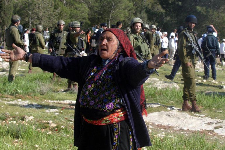 An elderly Palestinian woman reacts as Israeli soldiers prevent settlers from attacking Palestinian farmers ploughing their land near Maoun settlement, south of Hebron, 19 March 2005. Preparations quickened for Israel's pullout from the Gaza Strip as a Palestinian militant splinter group ended its informal truce, the first small chink in the fragile demilitarization of the four-year-old uprising. AFP PHOTO/Hazem BADER (Photo by HAZEM BADER / AFP)