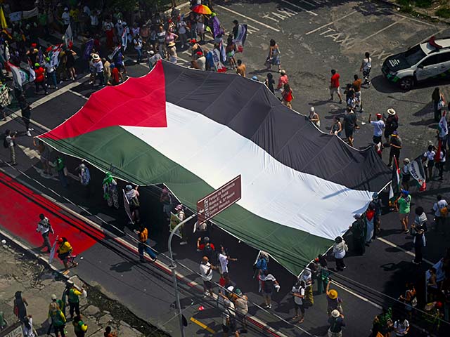ناشطون يحملون علماً فلسطينياً ضخماً خلال ما يسمى "المسيرة الشعبية العظيمة" على هامش مؤتمر الأمم المتحدة المعني بتغير المناخ COP30 في بيليم، ولاية بارا، البرازيل في 15 نوفمبر 2025. حضر الآلاف من الأشخاص المسيرة للمطالبة "حلول حقيقية" إلى ظاهرة الاحتباس الحراري التي يسببها الإنسان، والتي تأتي في منتصف الطريق من مفاوضات COP30 المثيرة للجدل بعد احتجاجين قادهما السكان الأصليون وعطلوا الإجراءات في وقت سابق من الأسبوع. (تصوير ماورو بيمنتيل / وكالة الصحافة الفرنسية) (تصوير ماورو بيمنتيل / وكالة الصحافة الفرنسية عبر غيتي إيماجز)