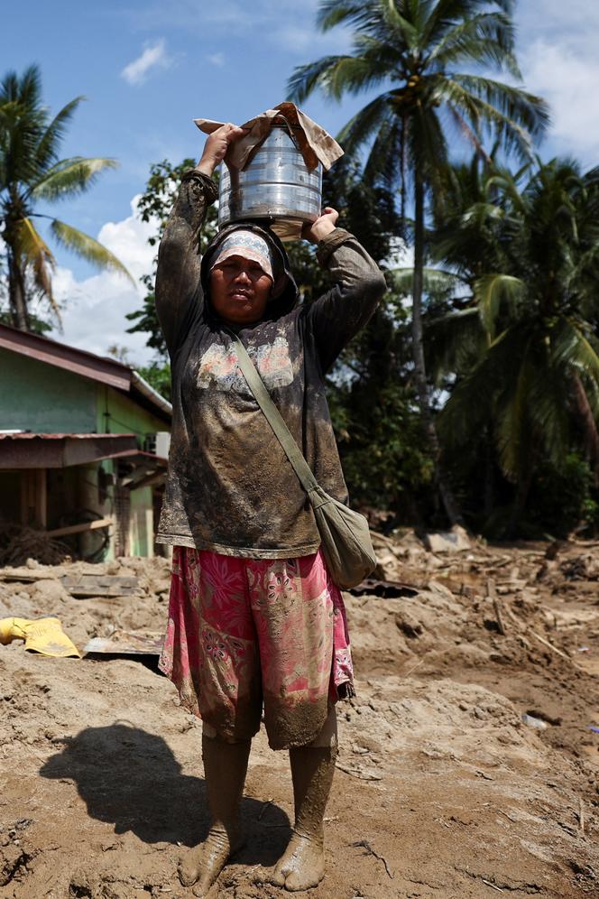 الناجية هيلين سيماري ماري، 48 عامًا، تحمل دلوًا من الأرز المطبوخ الذي وزعته خدمات الطوارئ، بعد أن فقدت منزلها في أعقاب الفيضانات القاتلة التي ضربت سومطرة، باتانج تورو، إندونيسيا، في 6 ديسمبر 2025. 