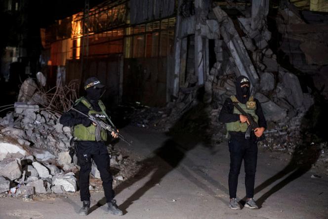 مقاتلو حماس يقفون للحراسة بينما تقوم مركبات الصليب الأحمر بنقل جثث الرهائن الذين تم تسليمهم إلى إسرائيل كجزء من اتفاق وقف إطلاق النار، 15 أكتوبر، 2025.